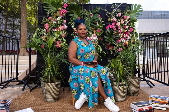 Mahogany L Browne sits against a flower wall set up at Lincoln Center