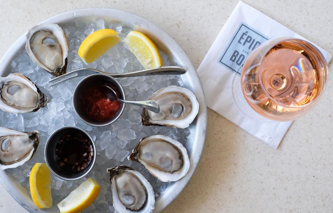 oysters on a plate of ice with a glass of rose beside it from epicerie boulud