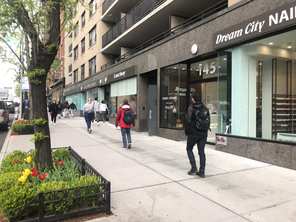 pedestrians walk along Amsterdam Ave in the spring