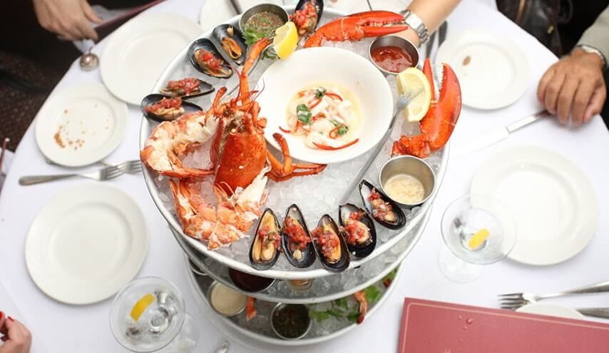 seafood spread on a table with hands reaching across to grab plates
