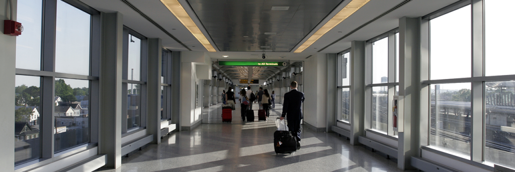 people walking down the pedestrian overpass with luggage at JFK Airport
