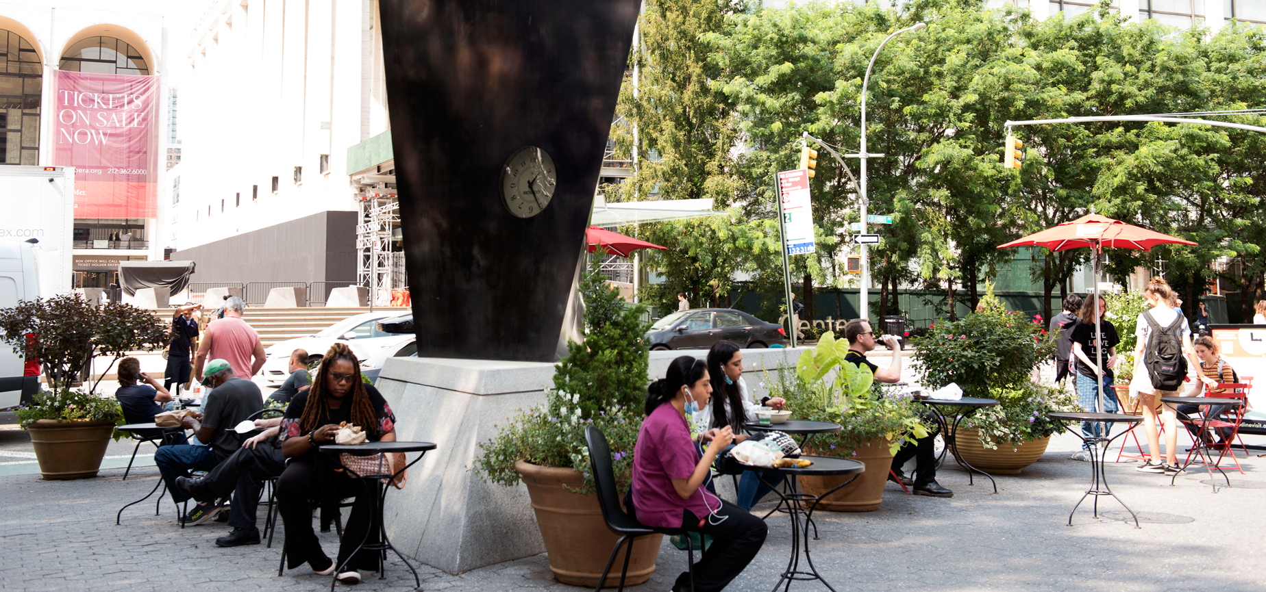 people sit at the tables and chairs provided by the LSBID around the movado clock in dante park