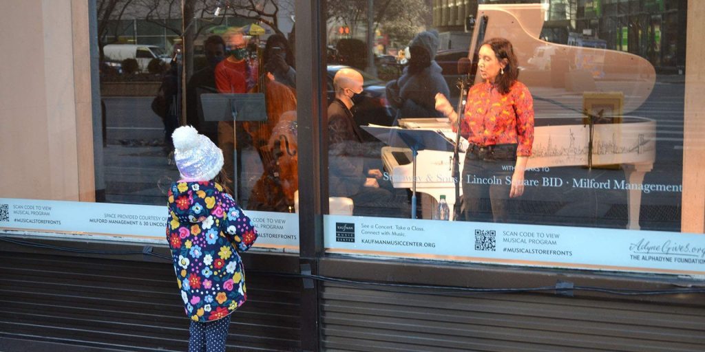little girl watching performers through a window