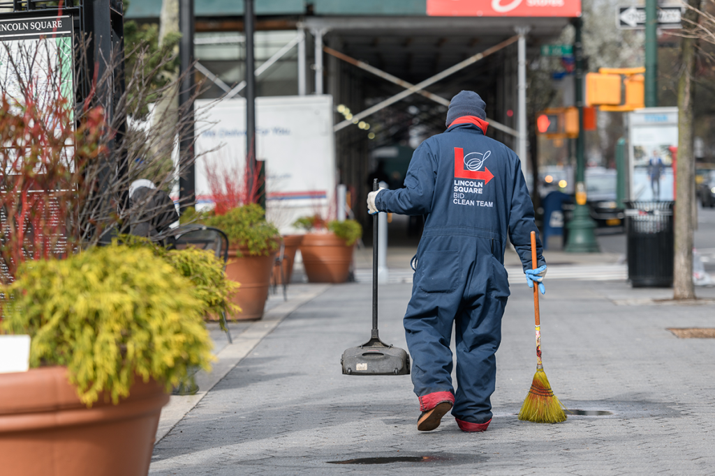 a clean team member walks along the sidewalk of Richard Tucker Park in March 2020
