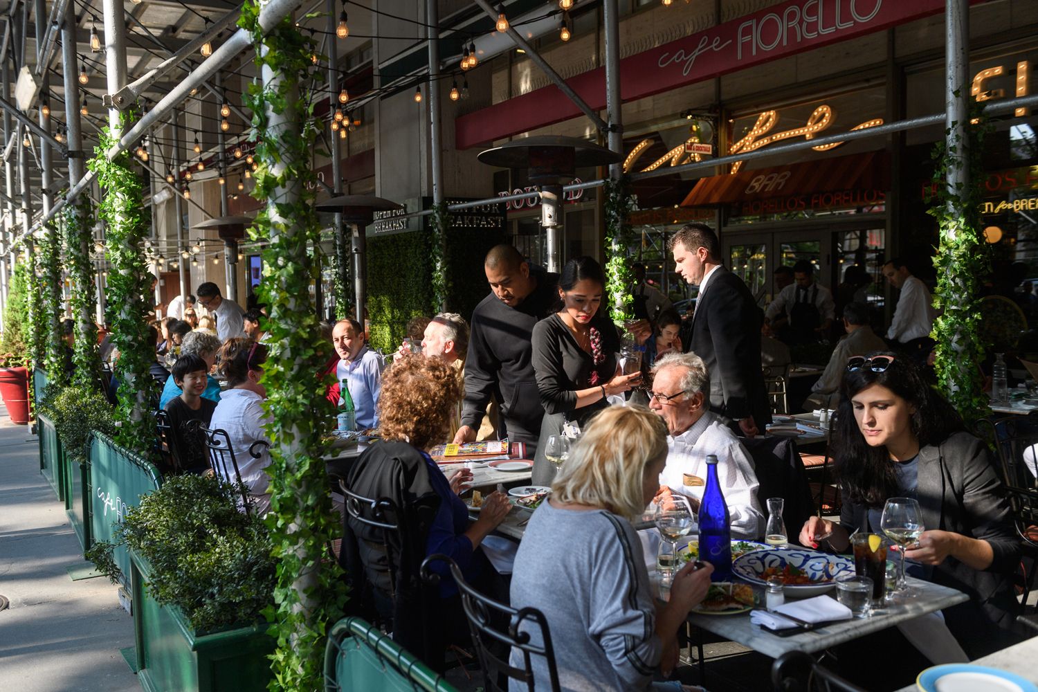 People dine in an outdoor seating area on Broadway in the summertime
