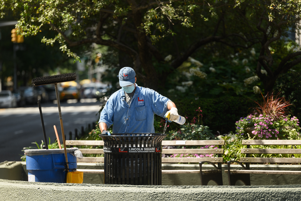 a clean team member cleans the edge of an LSBID branded trash can