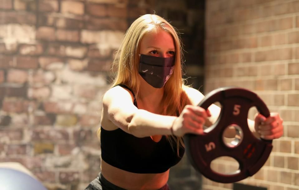 woman wearing a mask while lifting weights