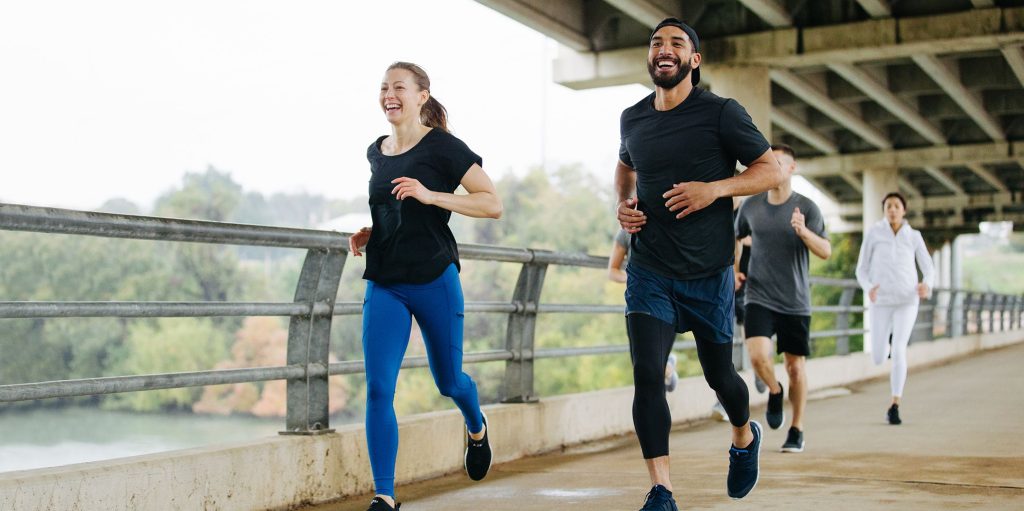 runners cross a pedestrian bridge in a park