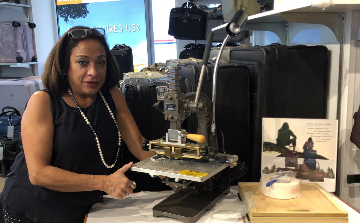 Store manager at Innovation Luggage poses with engraving machine in store