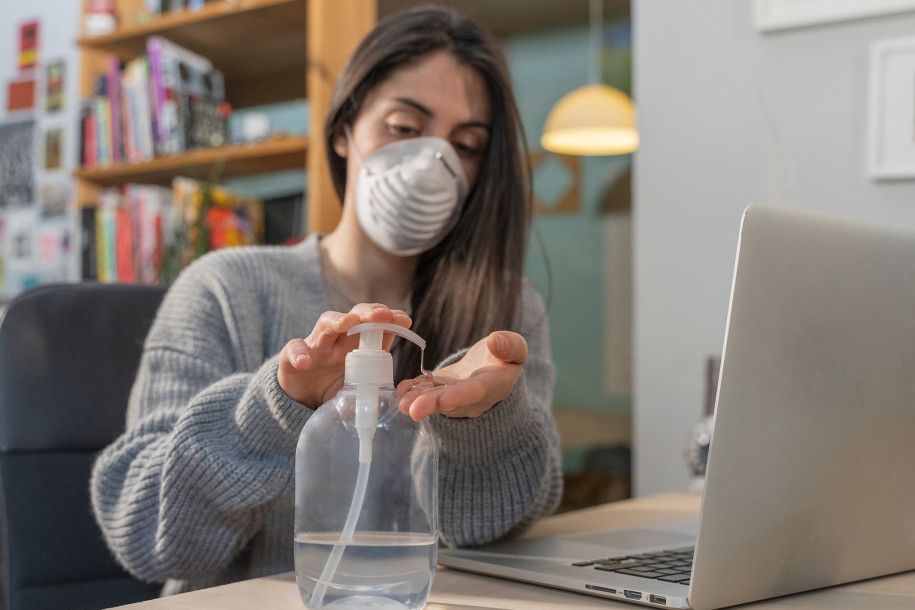 woman with a mask using hand sanitizer