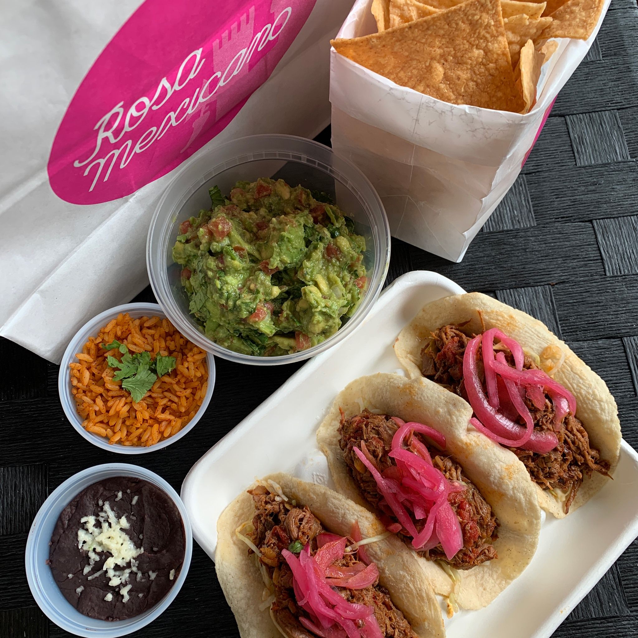 a spread of takeout tacos from rosa mexicano with quacamole and salsa sides