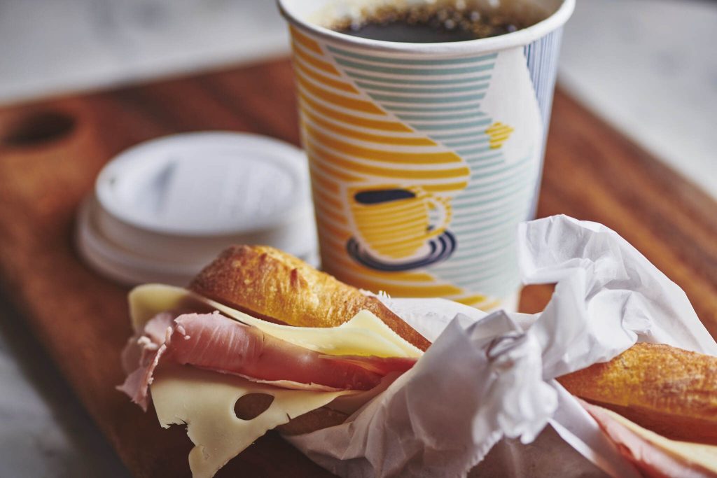 to-go cup of coffee from Tartinery with ham and cheese sandwich