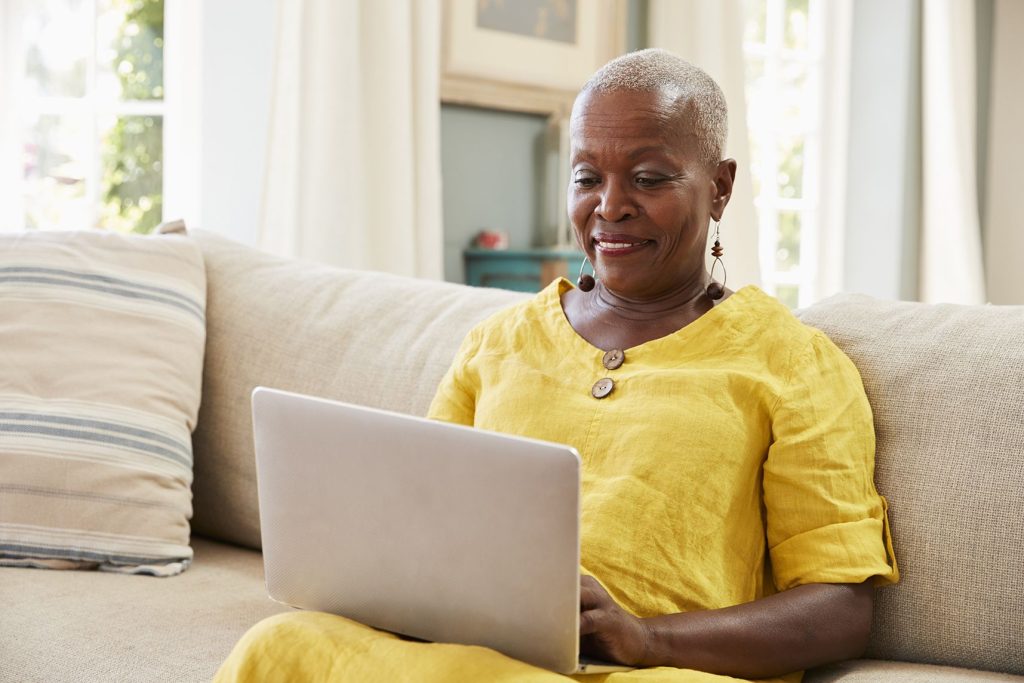 an older woman uses her laptop on her living room couch