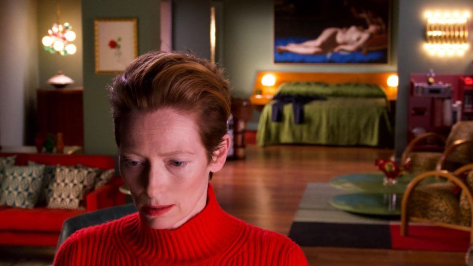 tilda swinton close up to the camera with a living room setting in the background