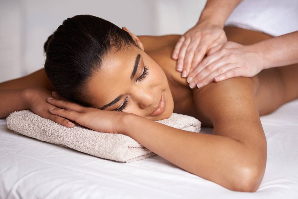 a woman receives a shoulder massage while lying down on a massage table at Upper West Spa