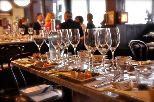 wine glasses lined up on a wooden table with small plates of food