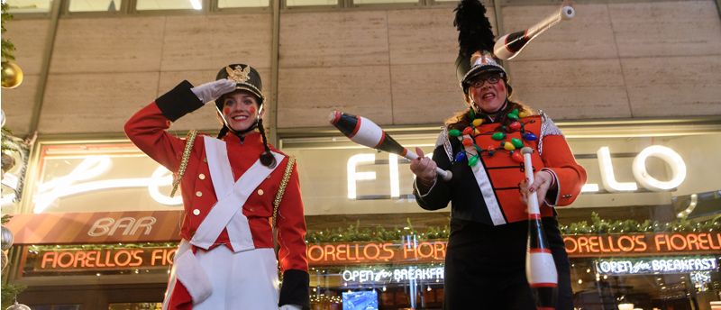 two stilt walkers dressed as soldiers pose for a photo on the street during Winter's Eve