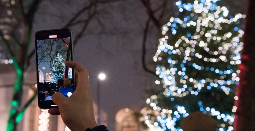 someone takes an iphone video of the Lincoln Square holiday tree during winters eve