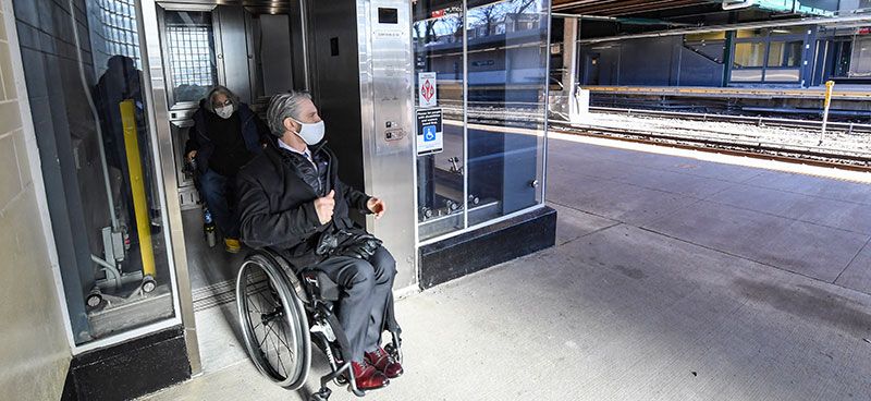 man in wheel chair entering train station