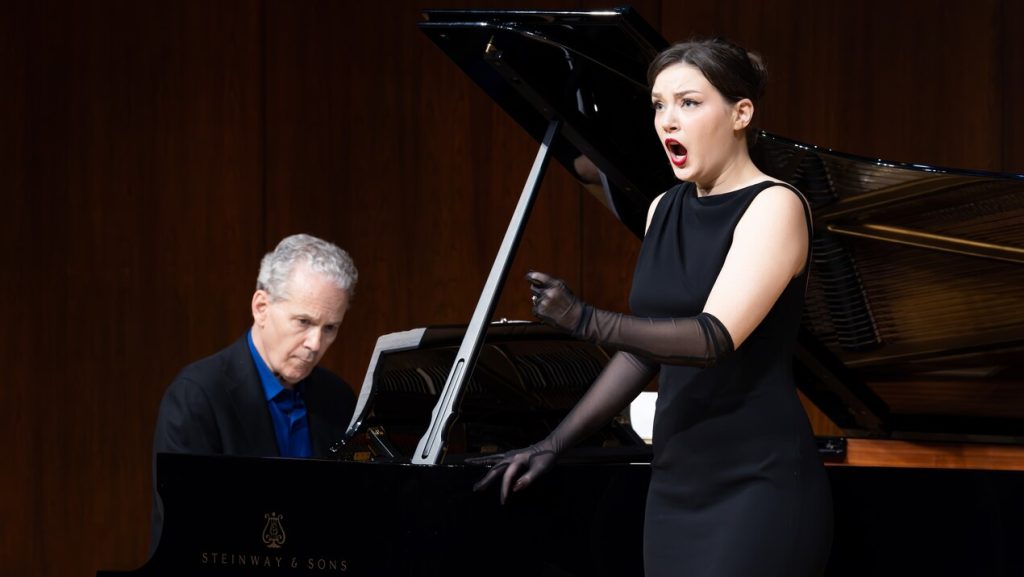 Photo of a woman singing and a man playing the piano